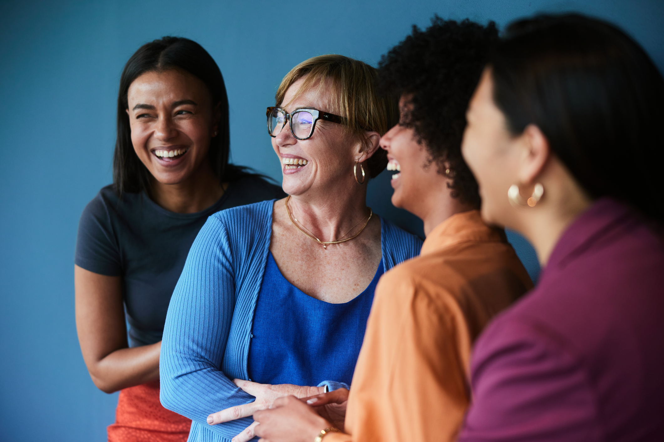 market intelligence services-Diverse group of businesswomen laughing against a blue background