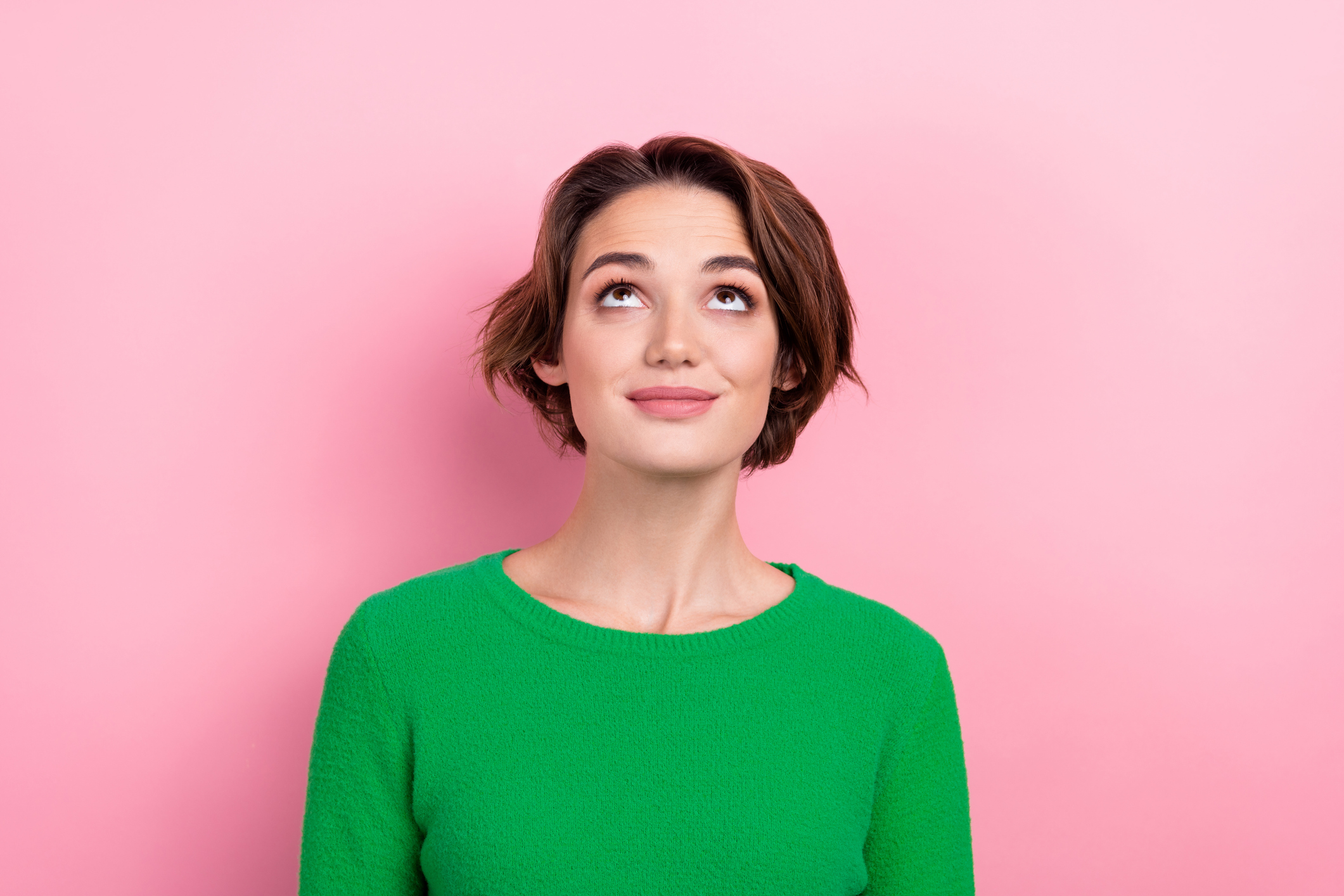 Photo of pretty cute girl wear stylish sweater clothes look up empty space interesting offer isolated on pink color background