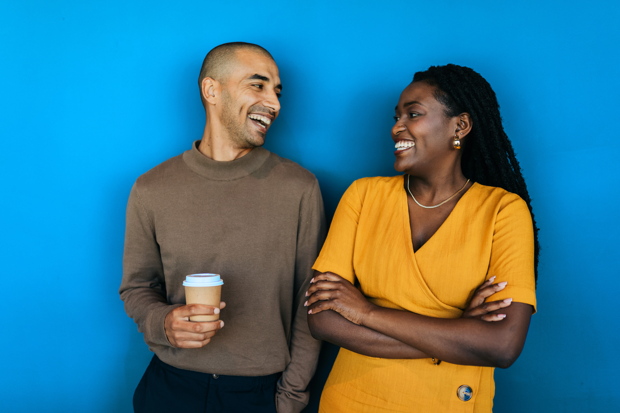 Portrait of business partners smiling cheerfully at each other against blue background