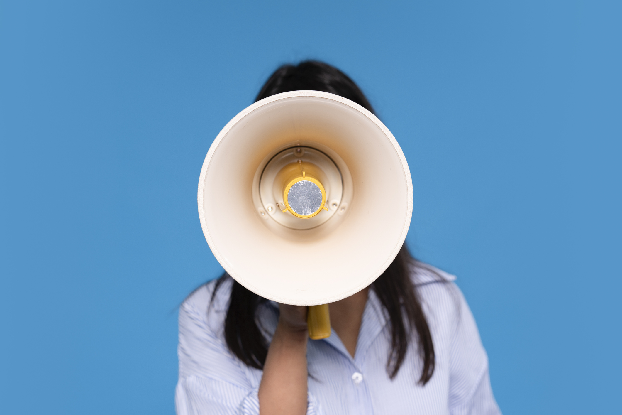 Woman Holding Megaphone Against Solid Blue Background