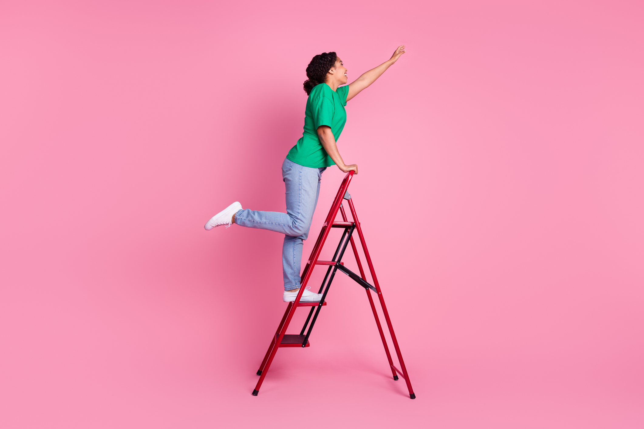 Full length photo of lovely young lady climbing ladder dressed stylish green garment isolated on pink color background